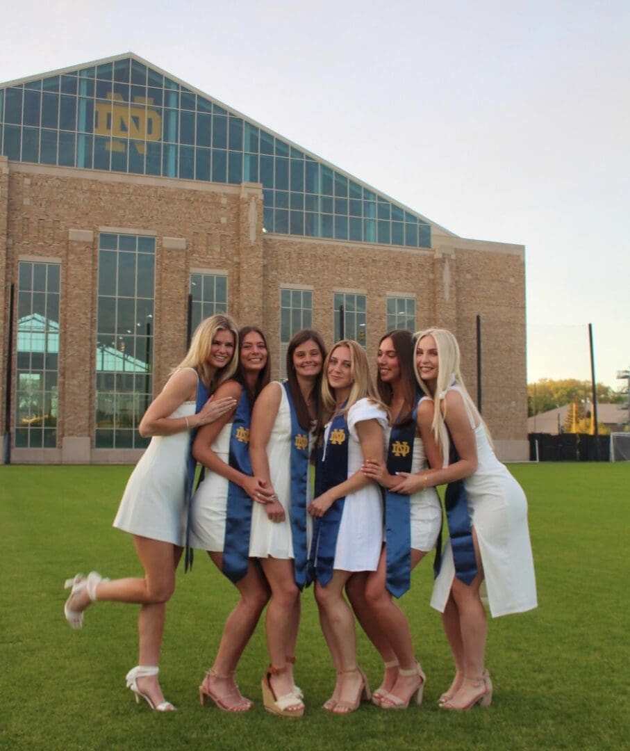 Six women in white graduation dresses.