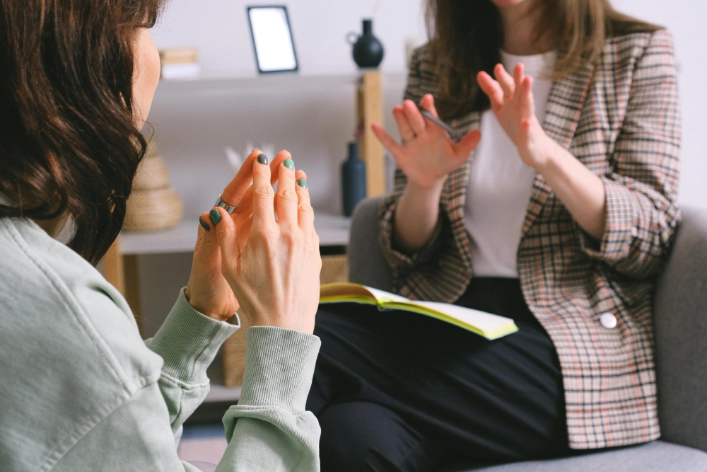 Two women sitting in a circle clapping hands.